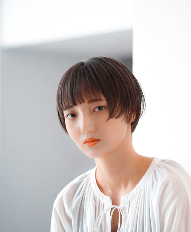 シンプルでありながら洗練されたフォルムのマッシュに、柔らかいベージュのヘアカラーで光が透けるような上品さをプラスしたコンパクトなショートスタイル